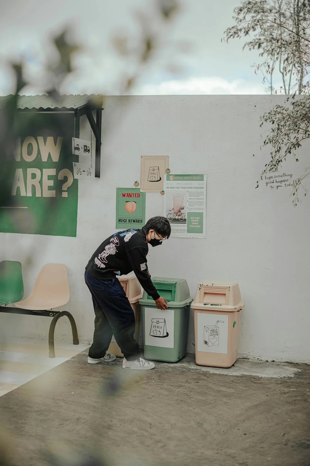 A man cleaning a glass barrier outdoors with a squeegee, surrounded by greenery.